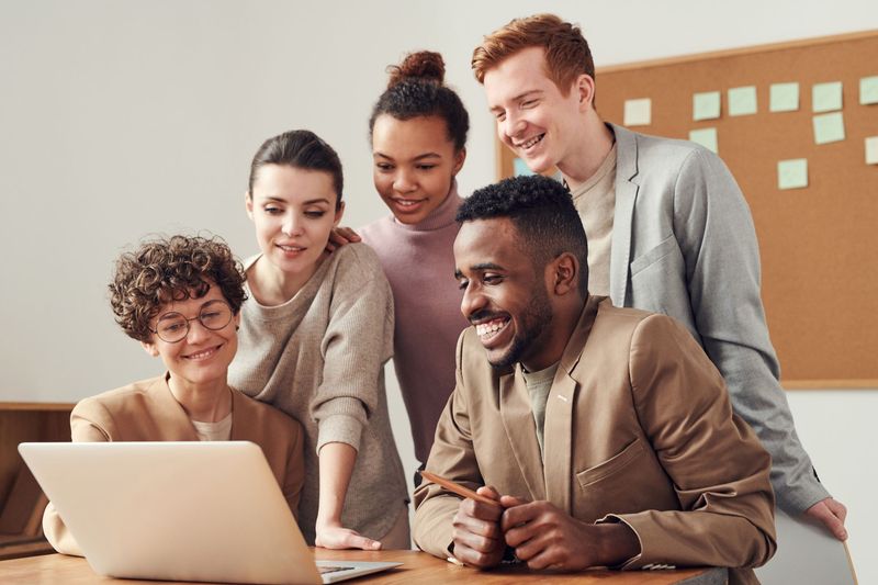 Next Target team members celebrating a win around a laptop