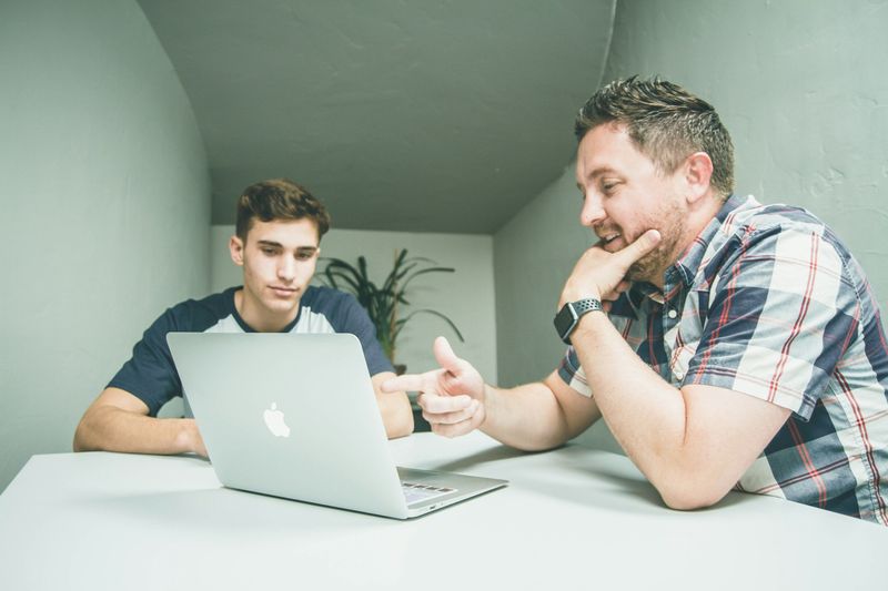 Mentor coaching a new team member at a laptop