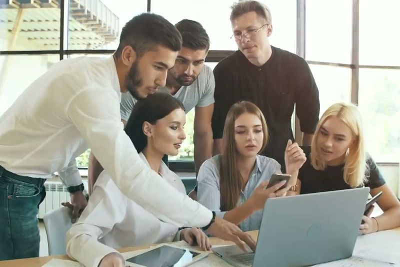 Next Target team members collaborating around a laptop